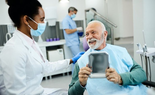Older man talking with dental team member