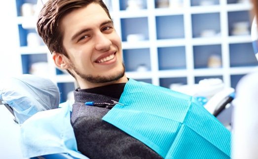: Male dental patient leaning back and smiling
