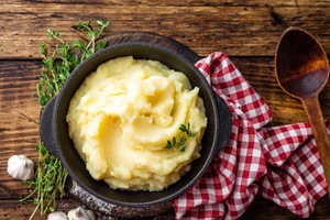 Bowl of mashed potatoes next to wooden spoon