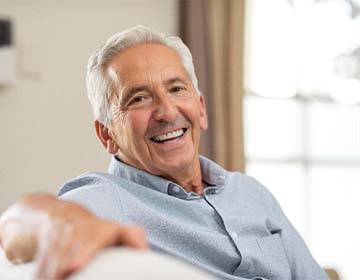 smiling man with dental implants in Carlisle, PA sitting on a couch