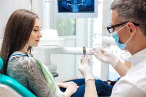 madentist showing a dental implant to a patient