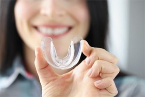 A woman holding a mouthguard in her hand 
