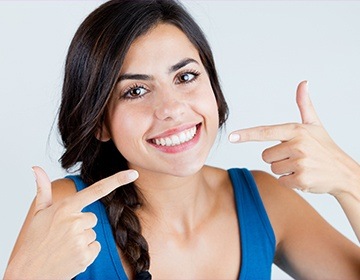 Woman pointing to her bright white smile